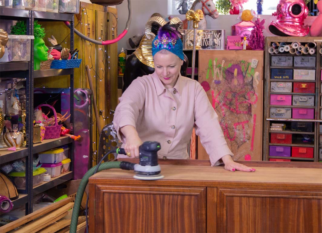 Zoe Pocock in her workshop sanding a sideboard